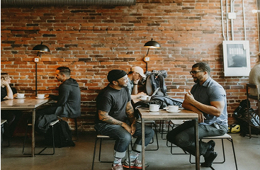 Coworkers chatting over coffee at a shared table
